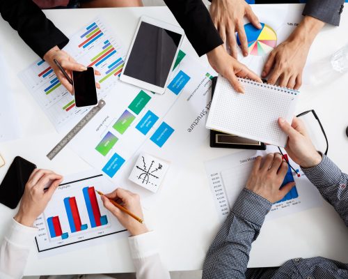 Picture of businessmen's hands on white table with documents, coffee and drafts